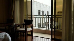 A hotel room with a balcony, a bed, a desk, and a chair. - Jinhui Hotel (Yangjiang)