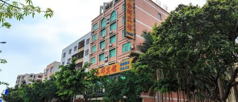 A multi-story hotel with a prominent entrance, surrounded by trees and parked cars.