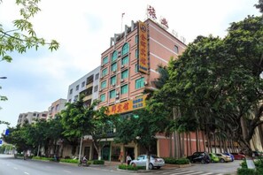 A multi-story hotel with a prominent entrance, surrounded by trees and parked cars. - Jinhui Hotel (Yangjiang)