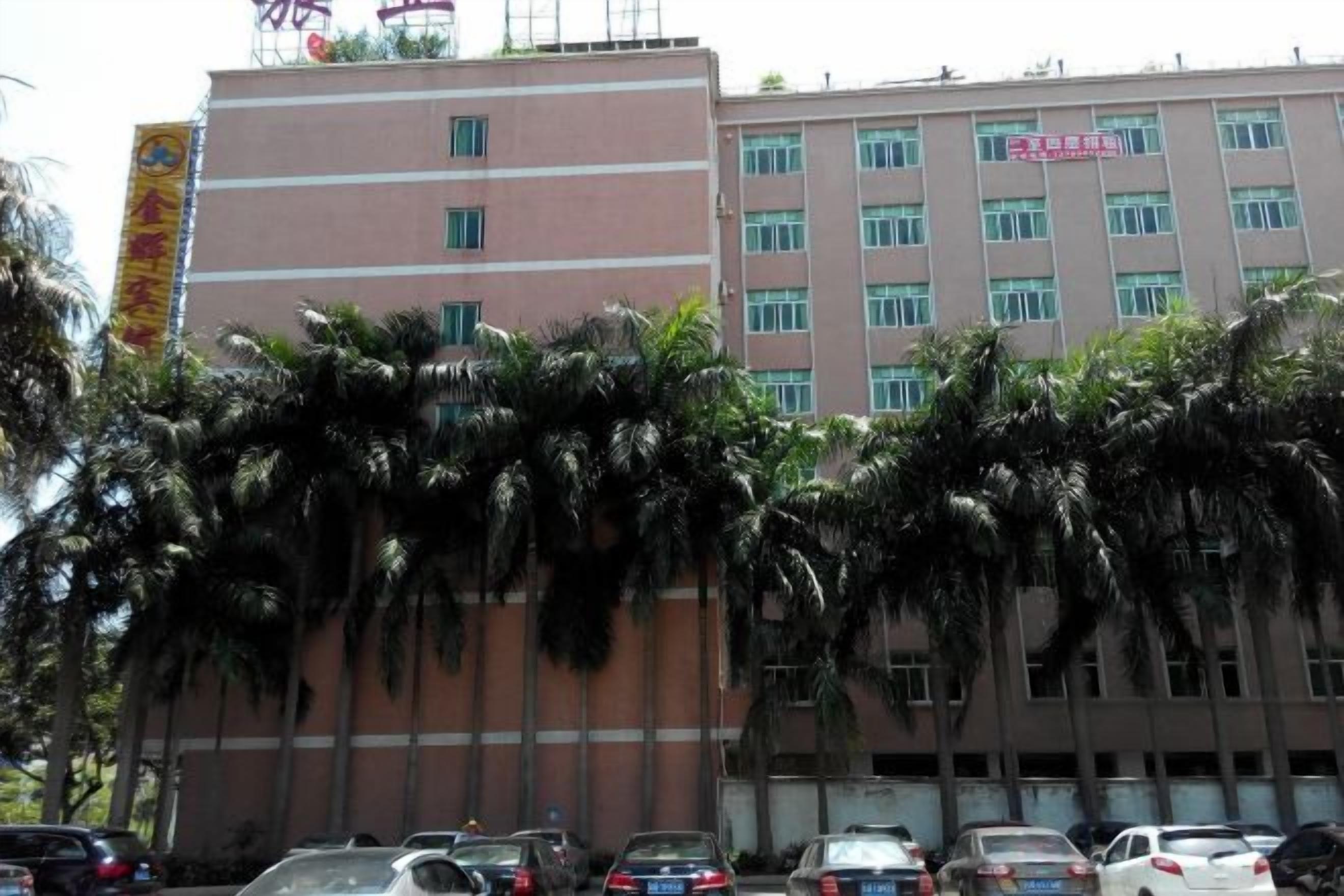 A multi-story building with a flat facade, several windows, and a parking lot with cars.