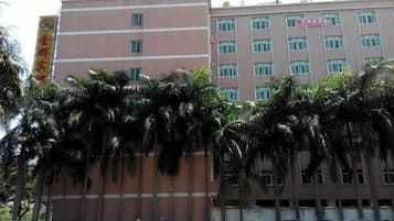 A multi-story building with a flat facade, several windows, and a parking lot with cars.
