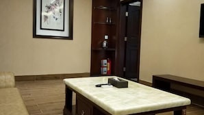 A hotel lobby with a reception desk, a framed artwork on the wall, a bookshelf, and a door. - Jinhui Hotel (Yangjiang)