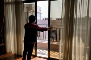 A person standing at a sliding glass door, likely entering or exiting a room. - Jinhui Hotel (Yangjiang)
