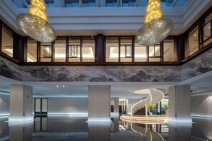 A spacious lobby with a marble floor, two large chandeliers, and a central spiral staircase. - Long Du Hotel (Hangzhou)