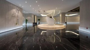 A modern lobby with a central spiral light fixture, polished marble floors, and minimalistic decor. - Long Du Hotel (Hangzhou)