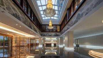 A spacious lobby with a high ceiling, a chandelier, and a marble floor.