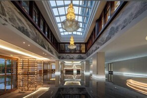 A spacious lobby with a high ceiling, a chandelier, and a marble floor. - Long Du Hotel (Hangzhou)