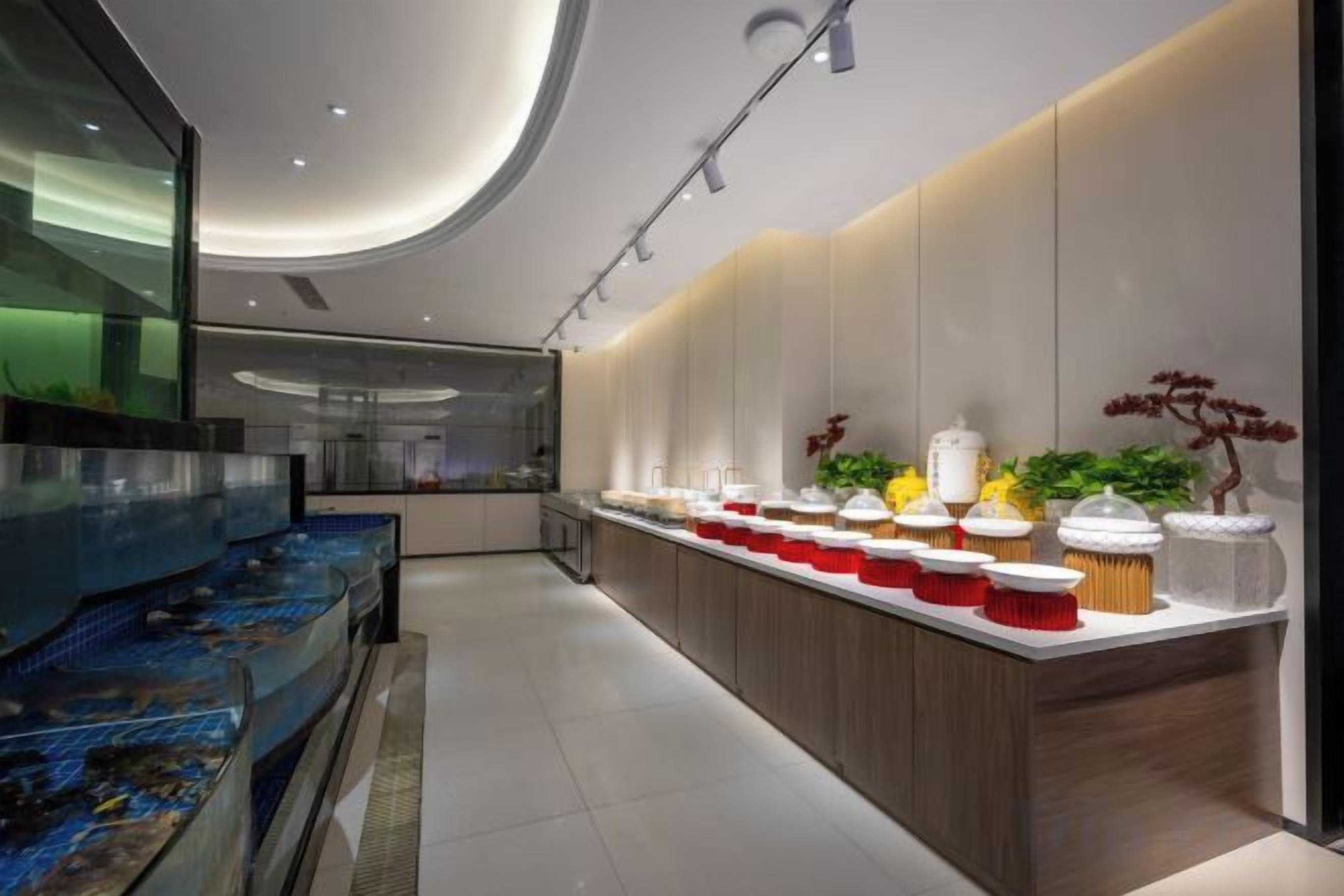 A modern kitchen with a long counter, a fish tank, and a variety of food items.
