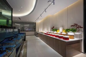 A modern kitchen with a long counter, a fish tank, and a variety of food items. - Long Du Hotel (Hangzhou)