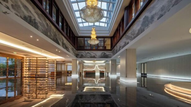A spacious lobby with a high ceiling, a central water feature, and a modern chandelier. - Long Du Hotel (Hangzhou)