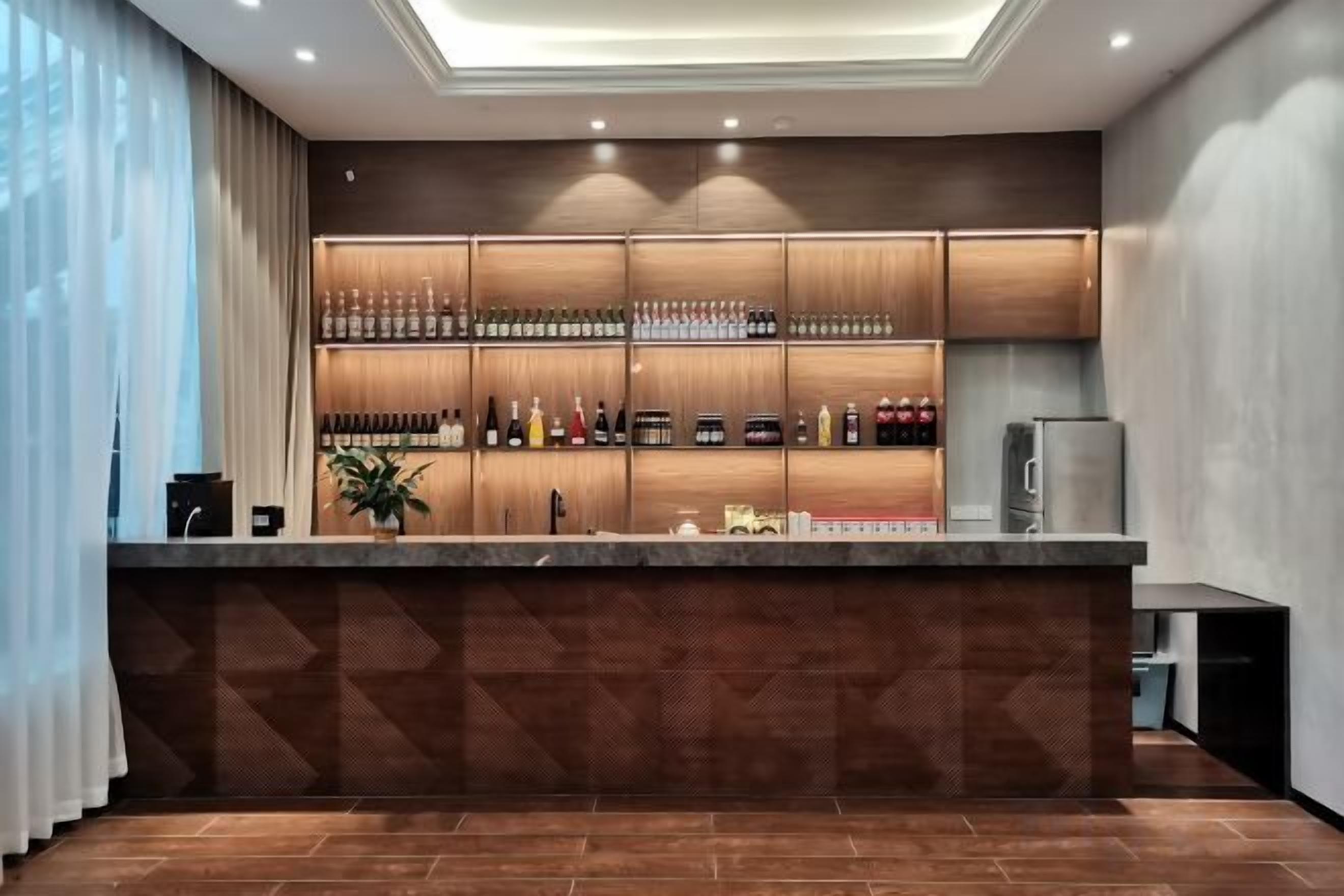 Zona de bar con mostrador, estanterías llenas de botellas y un refrigerador.