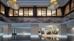 A spacious lobby with a high ceiling, large chandeliers, a marble floor, and a view of a staircase leading to upper floors. - Long Du Hotel (Hangzhou)