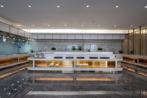 A modern hotel lobby with a central reception desk, marble flooring, and a glass partition. - Long Du Hotel (Hangzhou)