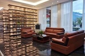 A modern living room with leather sofas, a coffee table, and a bookshelf. - Long Du Hotel (Hangzhou)