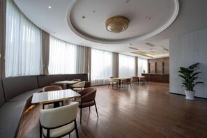 Un amplio vestíbulo de hotel con techo curvo, zonas de estar y un mostrador de recepción.