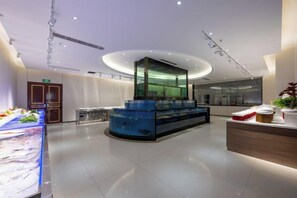 A modern hotel lobby with a central fish tank, a reception desk, and a seating area. - Long Du Hotel (Hangzhou)