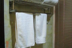 Ein Badezimmer mit zwei weißen Handtüchern an einem Metallgestell.