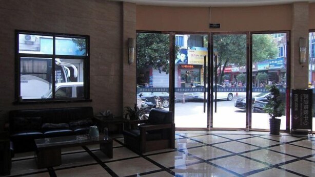 A lobby with a reception desk, seating area, and large glass doors leading outside.