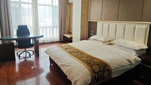 A hotel room with a large bed, a desk, and a chair.
