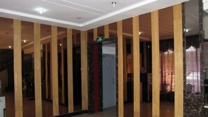 A hotel lobby with wooden columns, a marble reception desk, and a door with a red accent.