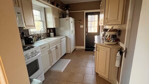 Una cocina con armarios blancos, estufa, refrigerador y microondas.