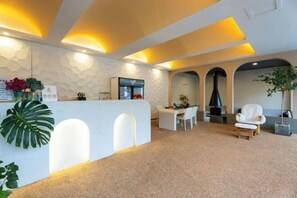 A reception area with a white counter, seating, and a plant. - Chongdugou Mochi B & B (Luanchuan)