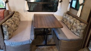 A compact RV interior with a central table and two cushioned benches. - In the Beautiful redwoodss, 2acres .20 minutes from Crescent city (Crescent City,)