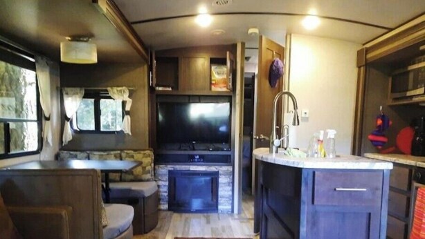 A compact RV interior with a kitchenette, a seating area, and a TV. - In the Beautiful redwoodss, 2acres .20 minutes from Crescent city (Crescent City,)