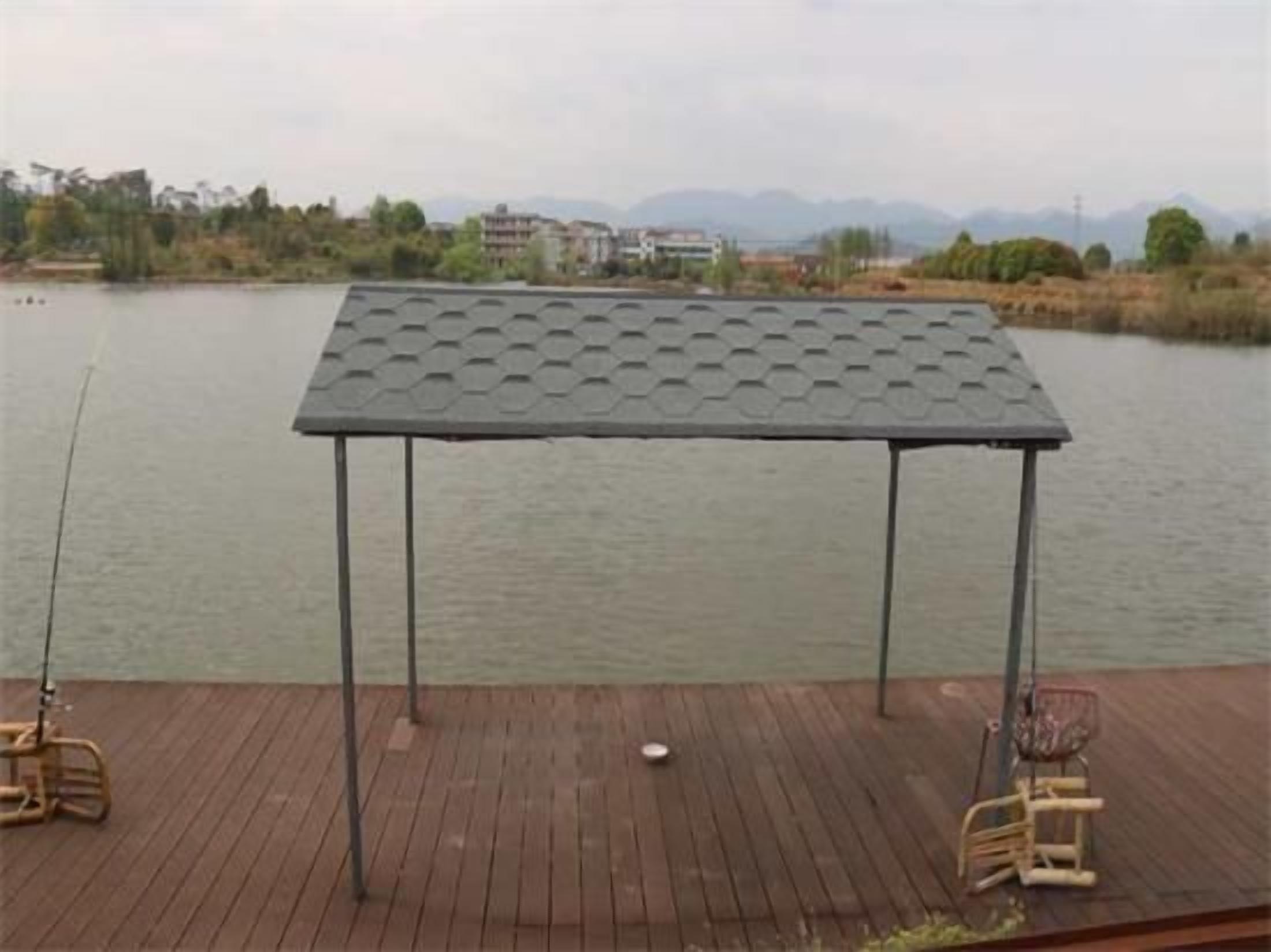 A covered outdoor area with a table and chairs, overlooking a body of water.