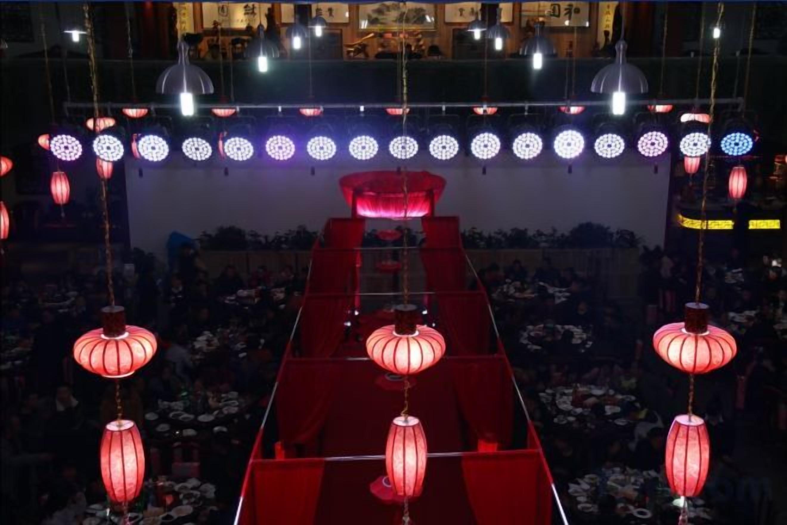 A red carpet event with hanging red lanterns and a tiered seating arrangement.