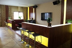 A bar area with a counter, stools, a TV, and potted plants. - Tiantai Feitou Chalet (Tiantai County)