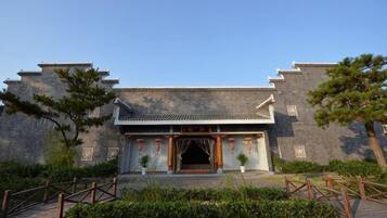 A traditional building with a tiled roof, a wooden entrance, and a stone wall.