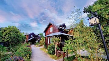 A pathway leading to a row of wooden houses with a street lamp on the right.
