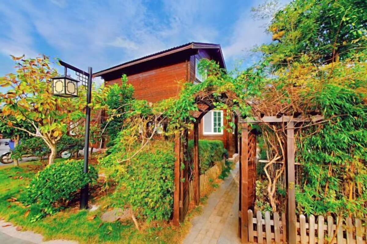 Una casa de madera con fachada de ladrillo, un portón de madera y un sendero que lleva a la entrada.