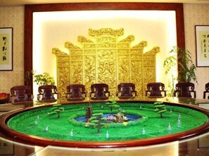 A reception area with a traditional Chinese-style backdrop, a round table with chairs, and a decorative fountain. - Tiantai Feitou Chalet (Tiantai County)