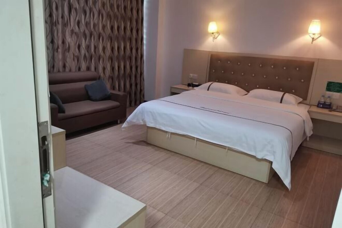 Una habitación de hotel con cama, mesita de noche, lámpara, sofá y pared con diseño.