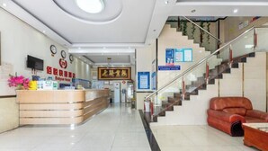 A hotel lobby with a reception desk, a staircase, and a leather sofa. - Baiyue Express Hostel (Dongguan)