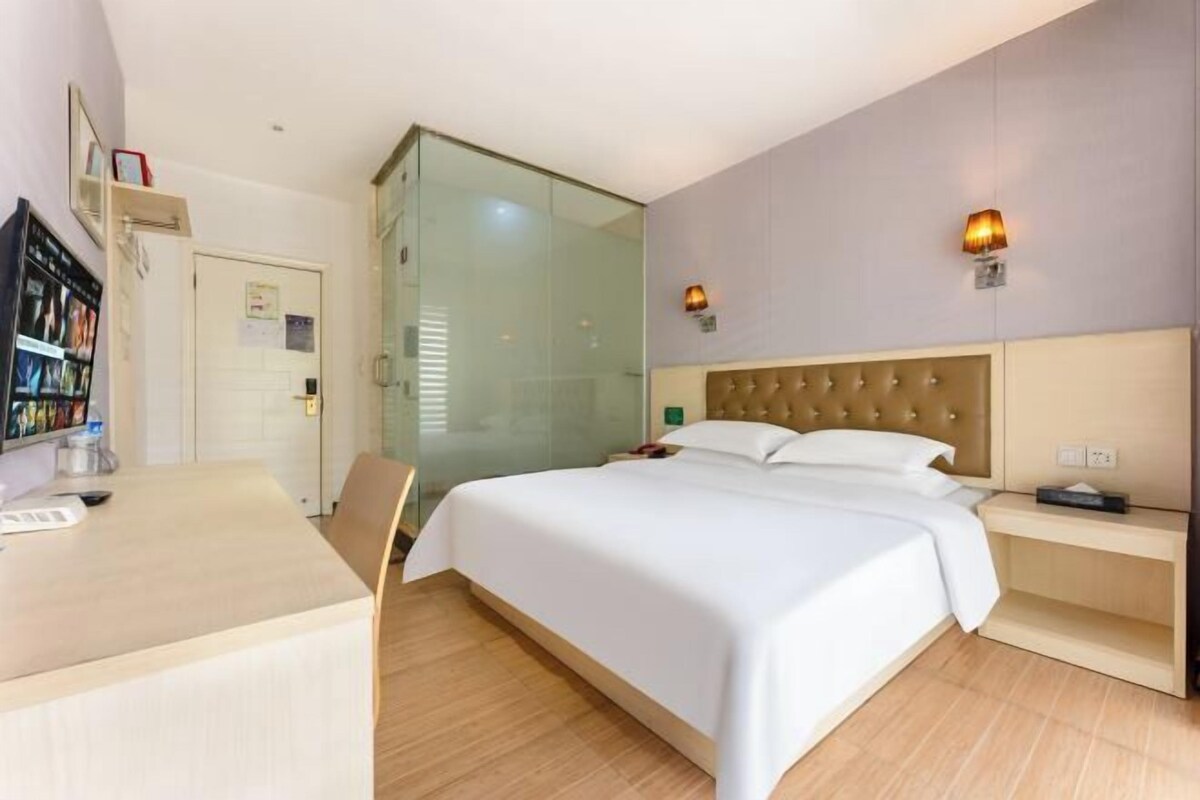 Una habitación de hotel con cama, mesita de noche y escritorio con silla.