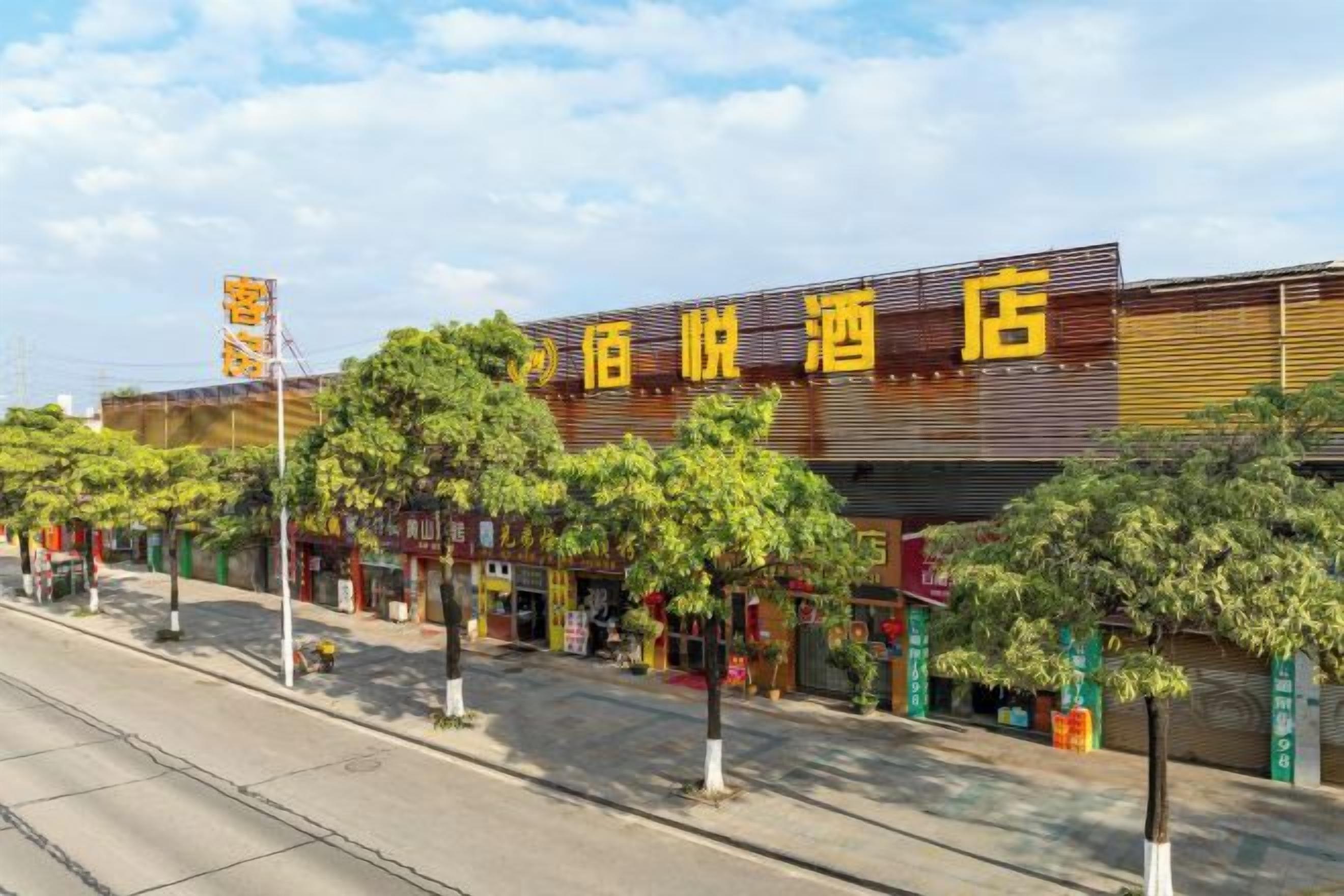 A hotel with a modern facade, multiple storefronts on the ground floor, and a clear sky above.