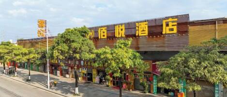 A hotel with a modern facade, multiple storefronts on the ground floor, and a clear sky above.