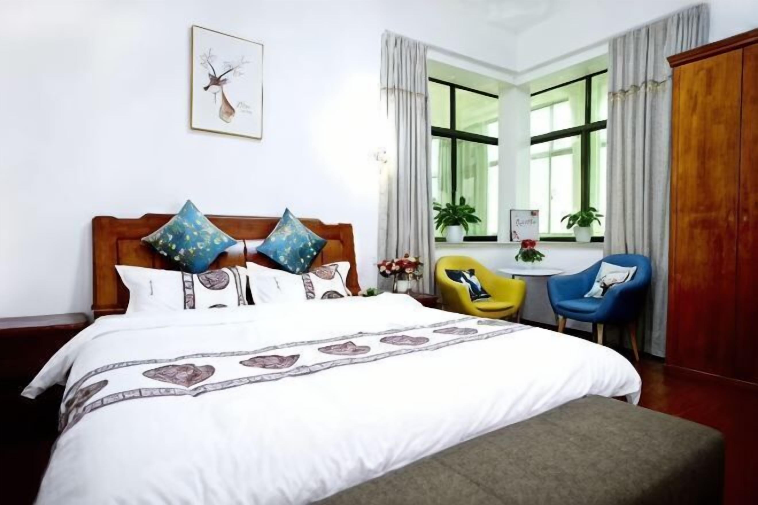 Een hotelkamer met een bed, een stoel, een bureau en een raam met gordijnen.