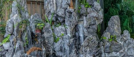 A rock garden with a water feature, including a small waterfall and various plants.