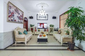 A living room with a sofa set, a coffee table, a television, and a potted plant. - Shanghai Tule Residential Accommodation (Shanghai)