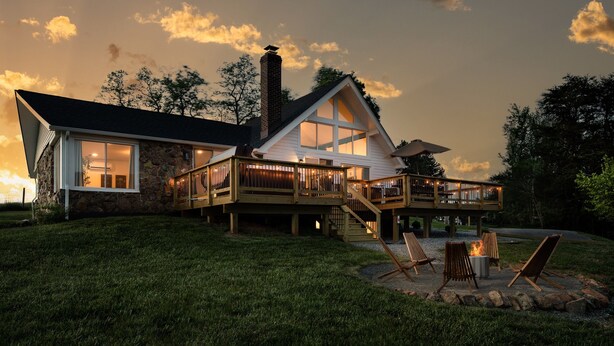 Ein geräumiges Haus mit einer Terrasse, Sitzgelegenheiten im Freien und einer Feuerstelle.