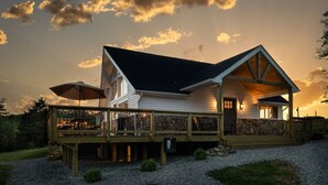Ein zweistöckiges Haus mit überdachter Terrasse und Natursteinfundament.