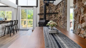 Eine moderne Küche mit einer Steinwand, einem Holzespeise-tisch und Blick ins Freie.