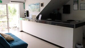 Un espace d’accueil avec un comptoir, un canapé bleu et un escalier.