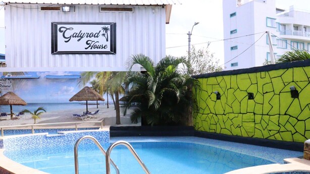 Un hôtel appelé « Calydrod House », doté d’une piscine, de chaises longues et d’une fresque murale sur le thème des tropiques.