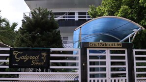 Une entrée fermée par un portail, avec une enseigne indiquant « Galydrod House » et une marquise bleue.