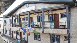 A multi-story building with balconies, air conditioning units, and a sign indicating a business or service establishment. - DF Plazza Hotel (Yaoundé)